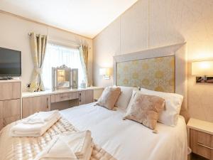 um quarto com uma grande cama branca e uma televisão em Tradmach Lodge em Patrington