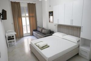een witte slaapkamer met een bed en een bank bij Xhani's Rooms in Durrës
