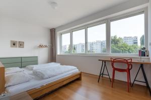 a bedroom with a bed and a desk and windows at Neu zentral und ruhig an der U2 / Stadion in Vienna