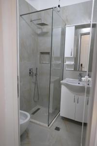 een badkamer met een douche, een toilet en een wastafel bij Xhani's Rooms in Durrës