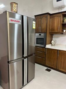 a stainless steel refrigerator in a kitchen with wooden cabinets at The luxury Home in Abha