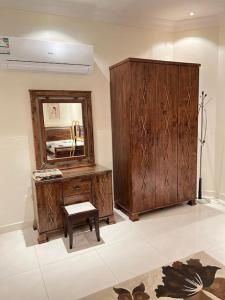 a bathroom with a mirror and a wooden cabinet and a stool at The luxury Home in Abha