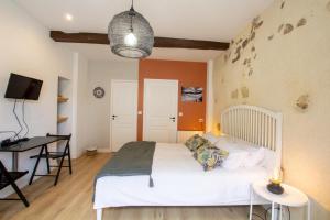 a bedroom with a white bed and a desk at Studio - Les Traversières in Eymet +29 photos