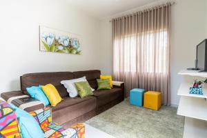 una sala de estar con un sofá marrón con almohadas coloridas en Casa Descanso Paraty, en Paraty