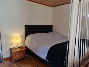 a bedroom with a bed and a night stand with a lamp at Paradiset in Kulltorp