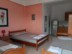 a bedroom with two beds and a kitchen with a refrigerator at Rexhos Studios in Himare