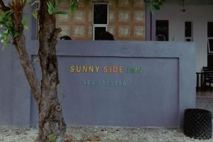 Una pared con un cartel que dice posada soleada en Sunny Side inn en Midu
