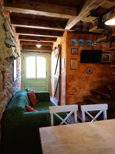 a living room with a green couch and a tv at Cottage al Merlo Olivo in Buje