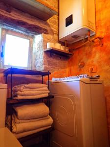 a laundry room with a washing machine and towels at Cottage al Merlo Olivo in Buje