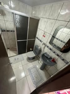 een badkamer met een wastafel, een toilet en een spiegel bij Quarto Deluxe em Foz piscina wifi estacionamento cozinha E AR in Foz do Iguaçu