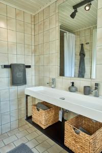 een badkamer met een wastafel, een spiegel en manden bij Modern vacation Home - Close to sea and nature. in Hejls