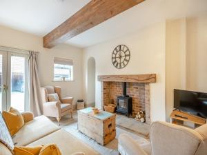 a living room with a fireplace and a tv at The Stables Cottage in Hemingby