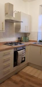 cocina con armarios blancos y fogones en Bowie's Abode en Sowerby Bridge