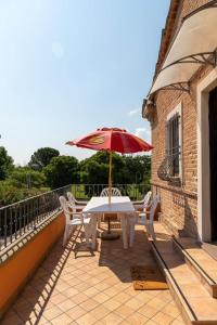 uma mesa e cadeiras com um guarda-sol numa varanda em Appartamento in villa em Fano