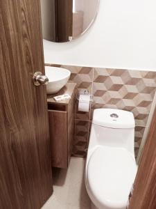 La salle de bains est pourvue de toilettes blanches et d'un lavabo. dans l'établissement Aw Hotel Pasarela Real, à Cali