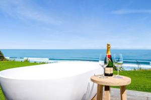 a bath tub with a bottle of champagne and two glasses at MOKAU BEACH HOUSE in Mokau