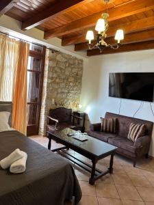 a living room with a couch and a flat screen tv at SeaFront Stone Suites in Vonitsa