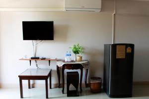 a living room with a table and a refrigerator at Pornkasem House in Chiang Rai
