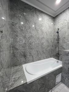 ein Badezimmer mit einer weißen Badewanne und einer Dusche in der Unterkunft ЖК - 4 YOU - Nomaden- 3 in Almaty