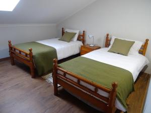a bedroom with two beds with green sheets at Casa das Andorinhas in Lourinhã