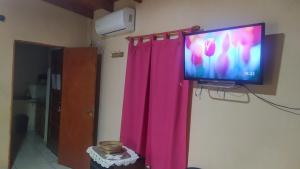 einen an einer Wand hängenden TV mit einem rosa Vorhang in der Unterkunft Apart Venecia in Puerto Iguazú