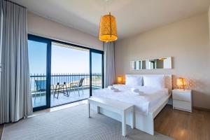 a bedroom with a large white bed and a balcony at Bovilla Hotel Yalıkavak in Yalıkavak