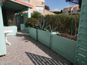 Una valla verde con plantas en una acera. en Appartement à 5mn de la plage en RdC, en Narbonne-Plage