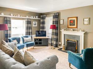a living room with a couch and a fireplace at Wanton Was Cottage in Penicuik