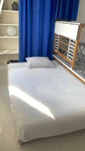 - un grand lit blanc dans une chambre avec un rideau bleu dans l'établissement *Blanche Pigalle* - Studio calme Paris centre, à Paris