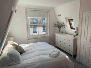 a bedroom with a large white bed and a window at A charming home in the heart of Southsea in Portsmouth