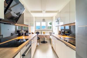 a kitchen with white cabinets and a table in it at Apartman Gratitude in Rijeka