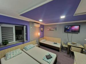 a room with two beds and a tv on the wall at Rooms Vedran in Mostar