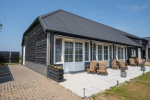 a black house with chairs and a patio at Johanneshoeve - de mooiste plek op Texel in Den Hoorn