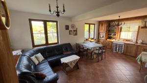 ein Wohnzimmer mit einem Ledersofa und einem Tisch in der Unterkunft Dom w sercu Kaszub in Parchowo