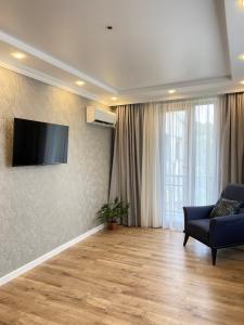 een woonkamer met een bank en een televisie aan de muur bij Апарт Отель in Poti
