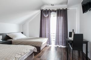 1 dormitorio con 2 camas, escritorio y ventana en Rezerwat85 en Gdansk