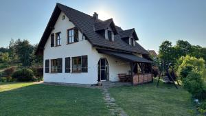 a white house with a black roof on a yard at Dom w sercu Kaszub in Parchowo