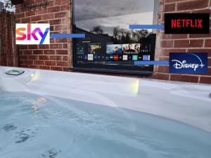 a hot tub with a tv in the background at Caban Cwtch - Log fire, pool table, hot tub cinema in Kent