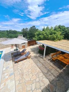 a patio with a table and chairs and an umbrella at Danino in Jezera