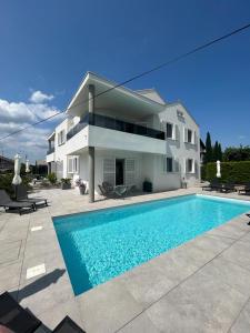 a house with a swimming pool in front of a house at Haus Dalmatia with heated Pool in Bibinje