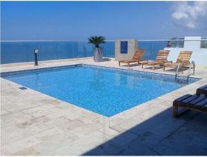 卡塔赫納的住宿－Prity Apartamento，一个带椅子的游泳池,背景是大海