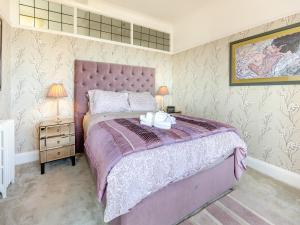 a bedroom with a bed with a purple comforter at Crossways Mansions in Bexhill