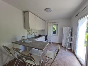 a kitchen with white cabinets and a table and chairs at Hiška na hribu in Ankaran