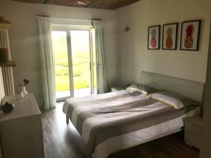 カスタニートにあるLe Aromatiche, appartamento in cascina con giardinoのベッドとガラスの引き戸のある寝室
