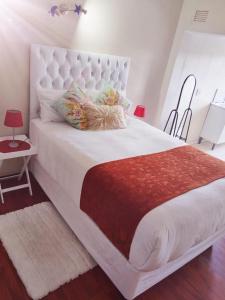Un dormitorio con una gran cama blanca con una manta roja. en Liyoli Guesthouse, en Mthatha