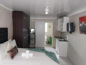 Mały pokój z białym łóżkiem i kuchnią w obiekcie Liyoli Guesthouse w mieście Mthatha
