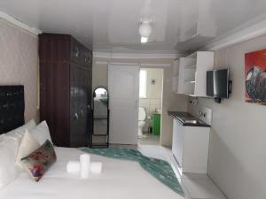 Habitación pequeña con cama blanca y cocina en Liyoli Guesthouse, en Mthatha