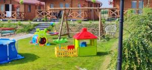 einen Spielplatz mit einem Spielhaus im Gras in der Unterkunft ZIELONA DOLINA - kompleks dla rodzin z dziećmi in Mikołajki