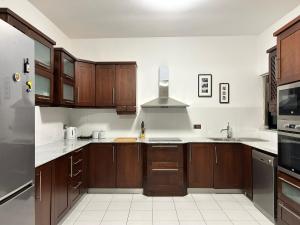 a kitchen with wooden cabinets and white tile floors at Galileo Rooms in Il- Gżira