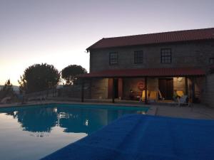 une maison avec une piscine en face d'un bâtiment dans l'établissement Quinta Do Quetrofe, à Guarda